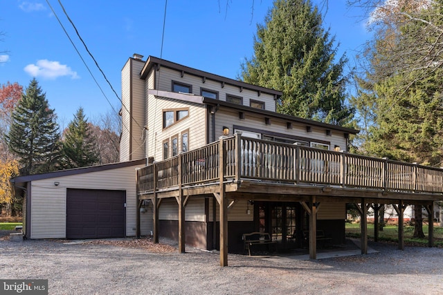 back of property with a garage and a wooden deck