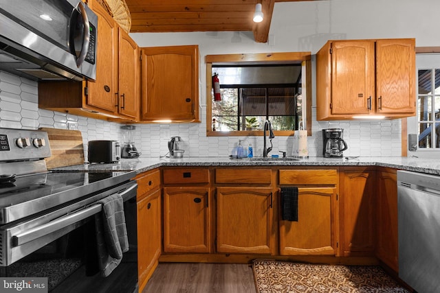 kitchen with sink, decorative backsplash, light stone countertops, wood ceiling, and stainless steel appliances