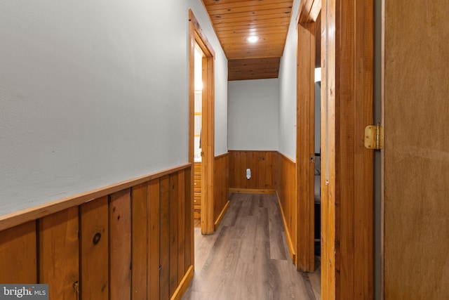 hallway with light wood-type flooring, wooden ceiling, and vaulted ceiling