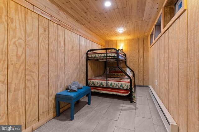 bedroom with a baseboard radiator, wood ceiling, and wood walls