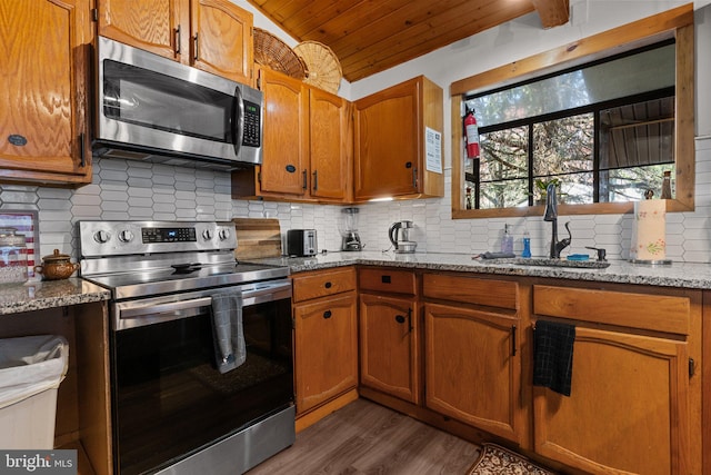 kitchen featuring light stone countertops, stainless steel appliances, dark hardwood / wood-style floors, vaulted ceiling, and wood ceiling