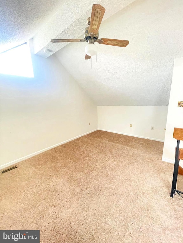 bonus room featuring a textured ceiling, carpet floors, ceiling fan, and lofted ceiling