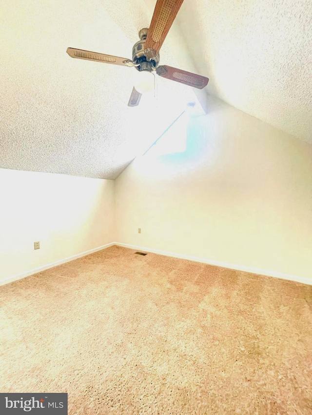 bonus room featuring lofted ceiling, carpet, a textured ceiling, and ceiling fan