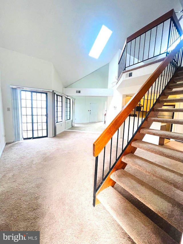 stairway featuring carpet, high vaulted ceiling, and a skylight