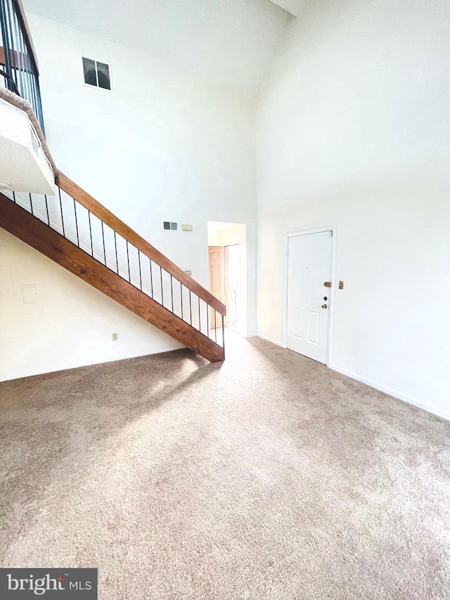 interior space with carpet flooring and high vaulted ceiling