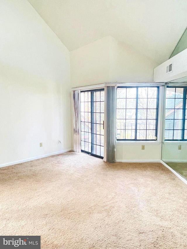 unfurnished room featuring carpet and high vaulted ceiling