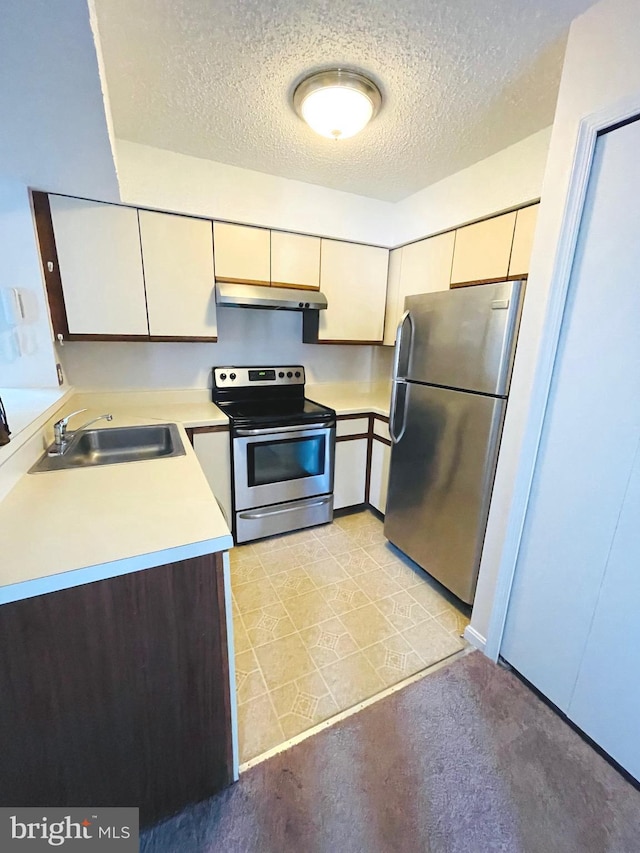 kitchen featuring appliances with stainless steel finishes, a textured ceiling, light tile patterned floors, and sink