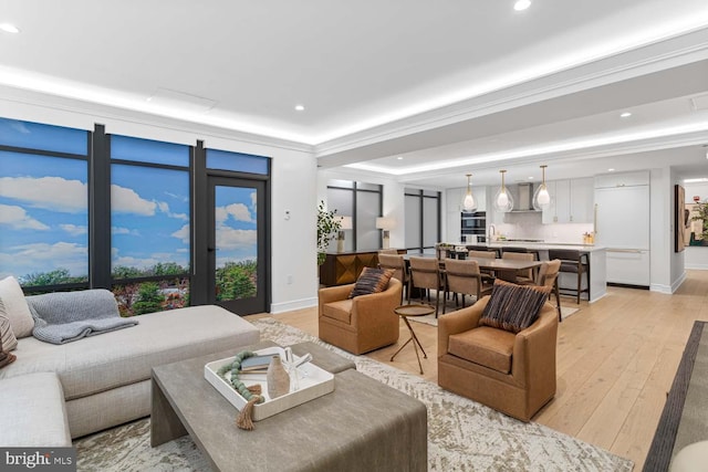 living room featuring ornamental molding, a tray ceiling, and light wood-type flooring