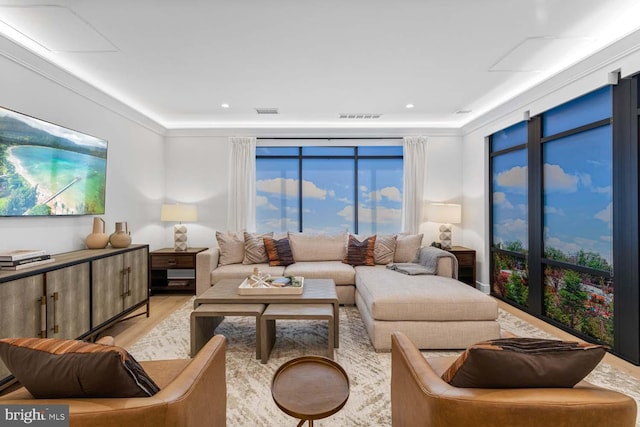 living room featuring a wall of windows, crown molding, and light wood-type flooring