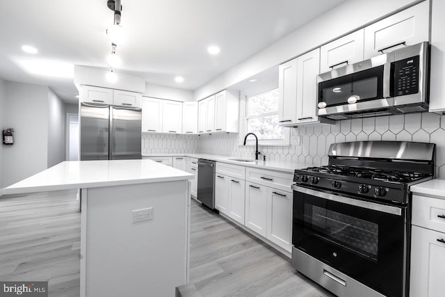 kitchen featuring sink, appliances with stainless steel finishes, a center island, and white cabinetry