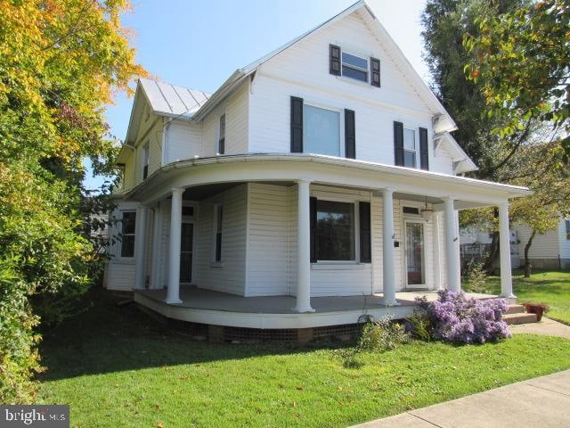 farmhouse inspired home with covered porch and a front lawn