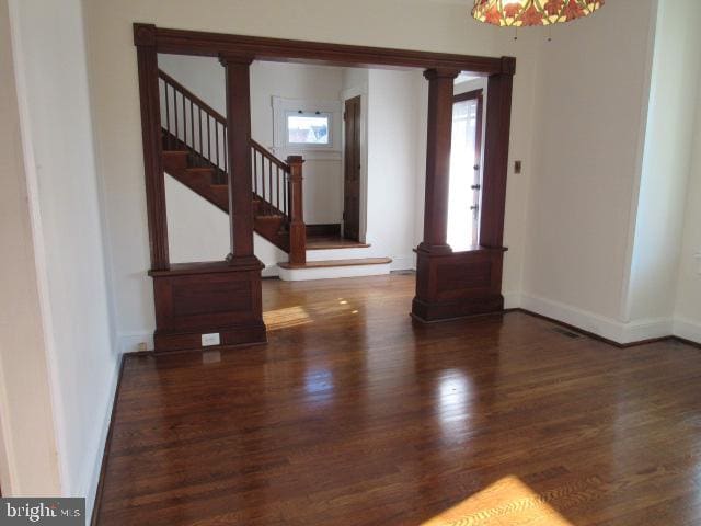 entryway featuring dark hardwood / wood-style floors, a chandelier, and decorative columns