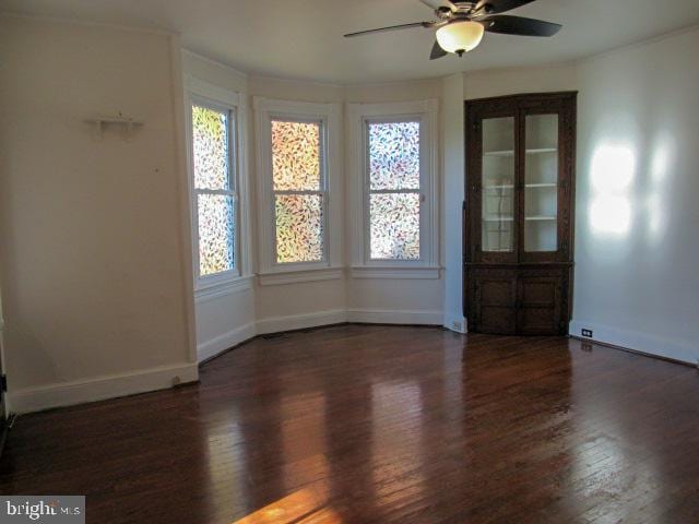 unfurnished room with dark wood-type flooring, ceiling fan, and a healthy amount of sunlight