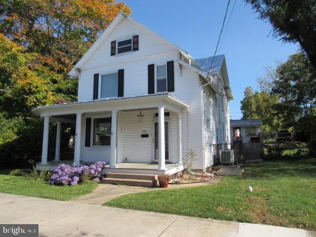 view of front of home with a front lawn, central AC, and covered porch