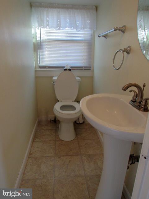 bathroom with toilet, sink, and tile patterned floors