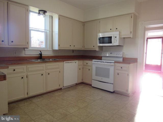 kitchen featuring white cabinetry, white appliances, and sink