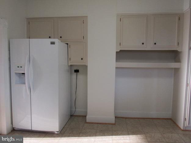 kitchen featuring white fridge with ice dispenser and white cabinetry