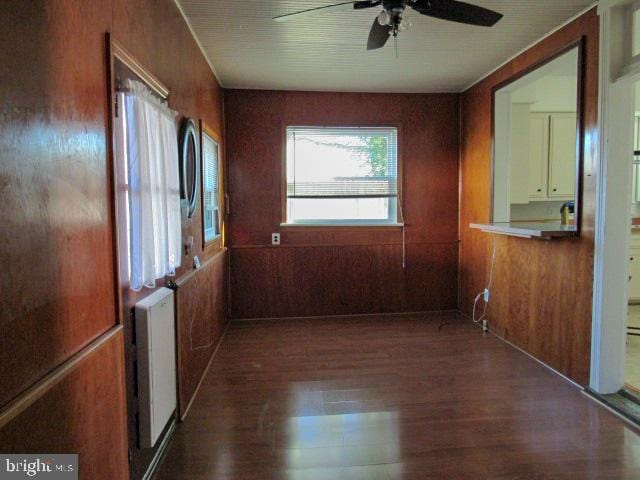 hall with wooden walls, dark hardwood / wood-style floors, and radiator