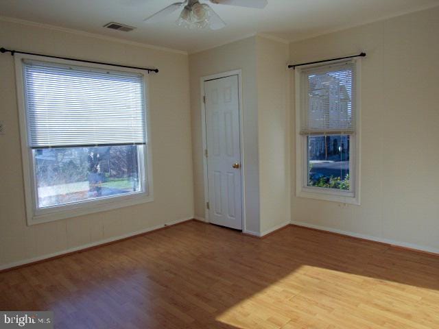 empty room with hardwood / wood-style floors, ceiling fan, and crown molding