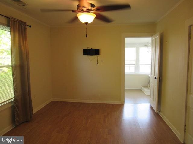 spare room featuring ceiling fan, a wealth of natural light, hardwood / wood-style flooring, and ornamental molding