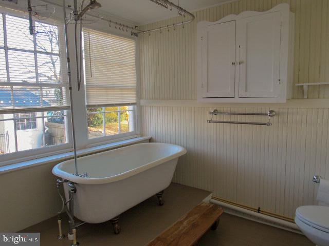 bathroom featuring wooden walls, toilet, and a bathtub