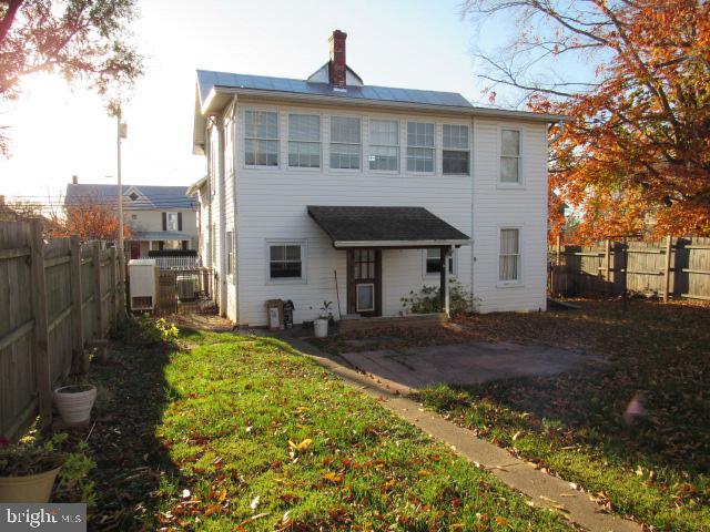 rear view of house with central air condition unit, a patio area, and a lawn