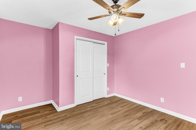 unfurnished bedroom with ceiling fan, wood-type flooring, and a closet