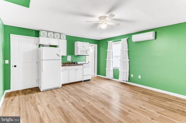 kitchen with ceiling fan, a wall mounted AC, white appliances, white cabinets, and light wood-type flooring