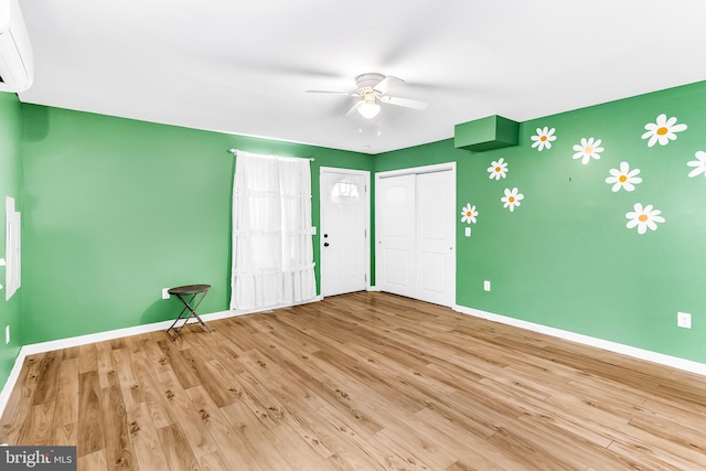 spare room featuring ceiling fan, light hardwood / wood-style flooring, and a wall mounted air conditioner