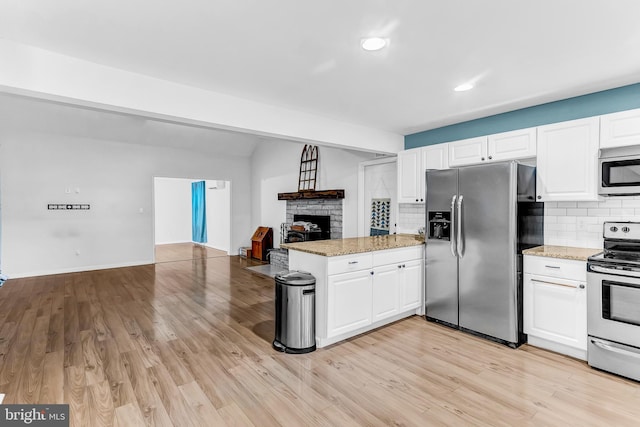 kitchen featuring kitchen peninsula, appliances with stainless steel finishes, light hardwood / wood-style flooring, and white cabinetry