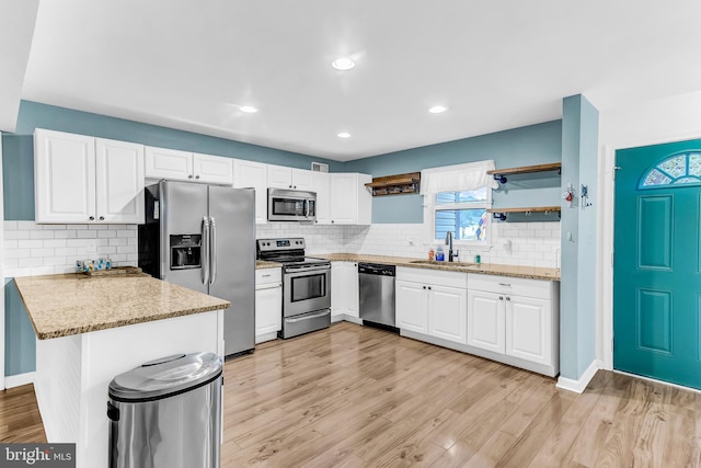 kitchen with sink, kitchen peninsula, light hardwood / wood-style floors, white cabinets, and appliances with stainless steel finishes