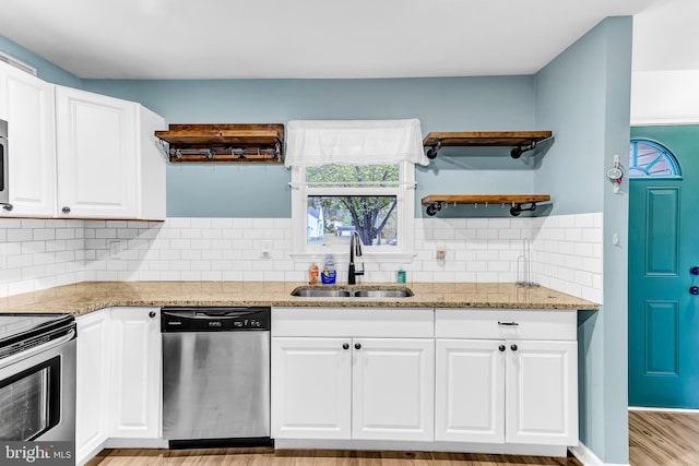 kitchen with appliances with stainless steel finishes, white cabinetry, light hardwood / wood-style flooring, and sink