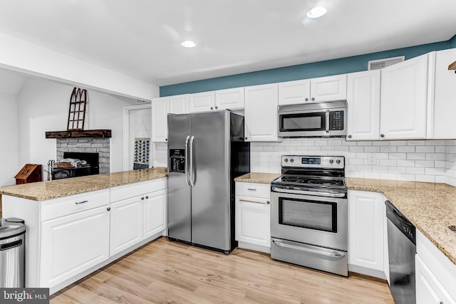 kitchen featuring kitchen peninsula, white cabinets, light wood-type flooring, and appliances with stainless steel finishes