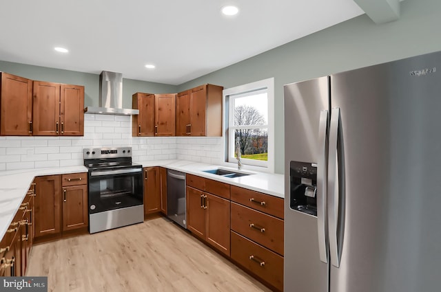 kitchen featuring sink, wall chimney exhaust hood, stainless steel appliances, backsplash, and light wood-type flooring