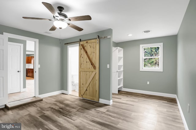 interior space with ceiling fan, a barn door, and wood-type flooring