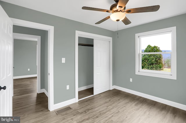 unfurnished bedroom featuring a closet, hardwood / wood-style flooring, and ceiling fan