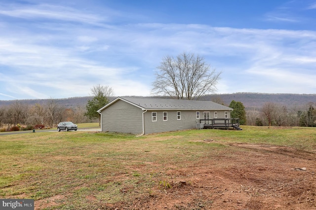 back of house featuring a lawn and a deck