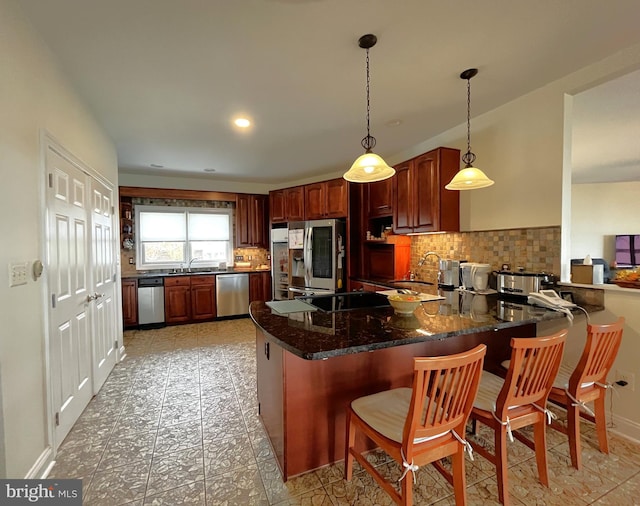 kitchen featuring hanging light fixtures, stainless steel appliances, a breakfast bar, backsplash, and kitchen peninsula