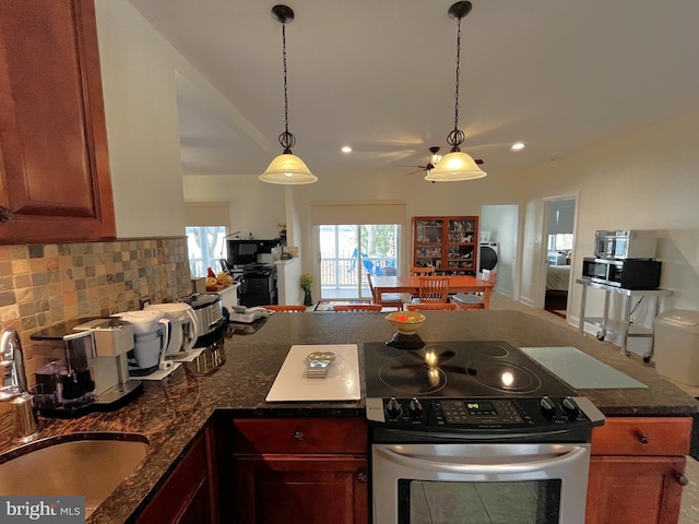 kitchen featuring decorative light fixtures, sink, backsplash, dark stone counters, and appliances with stainless steel finishes