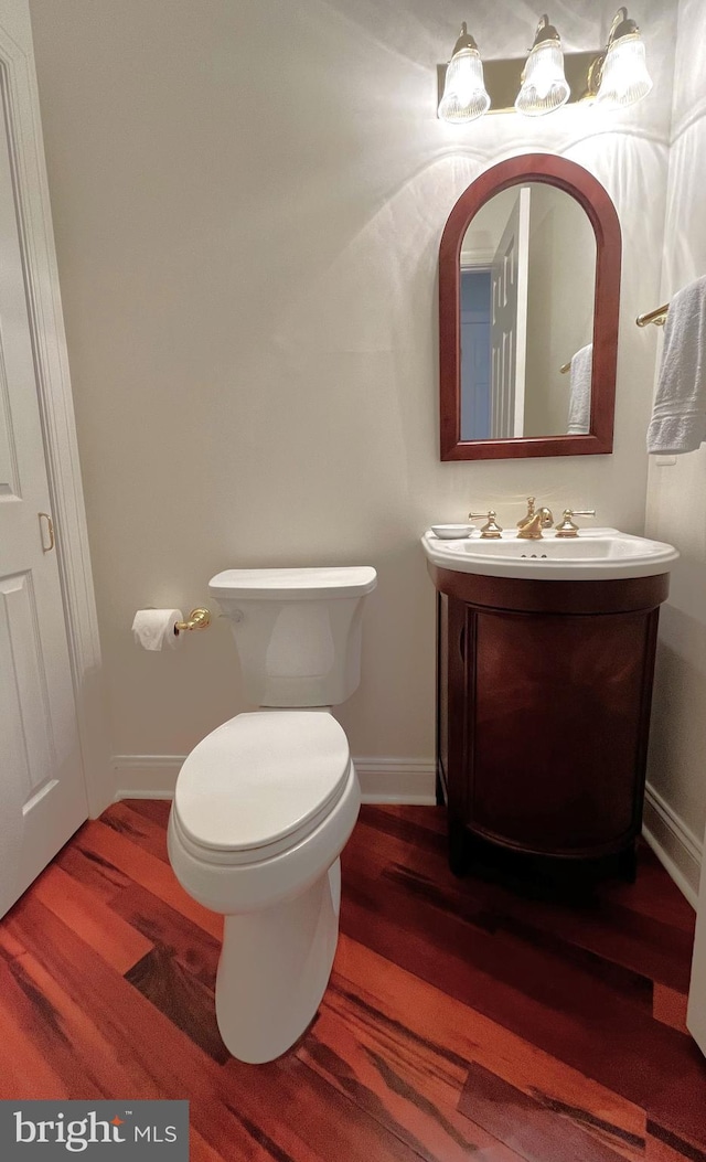 bathroom featuring toilet, vanity, and wood-type flooring