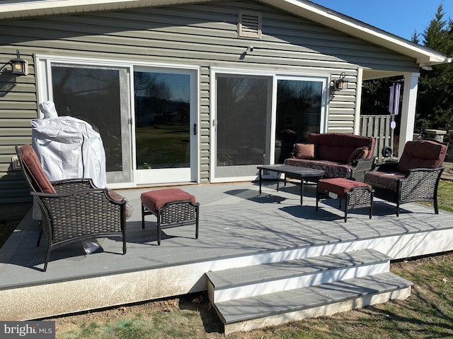 wooden deck with an outdoor living space and a grill