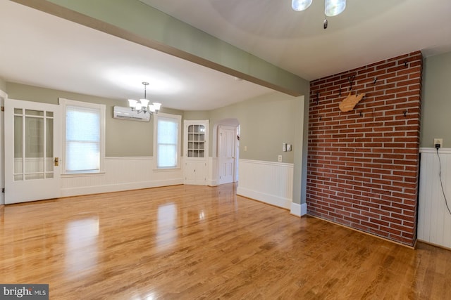 unfurnished dining area featuring a wall unit AC, a notable chandelier, and wood-type flooring