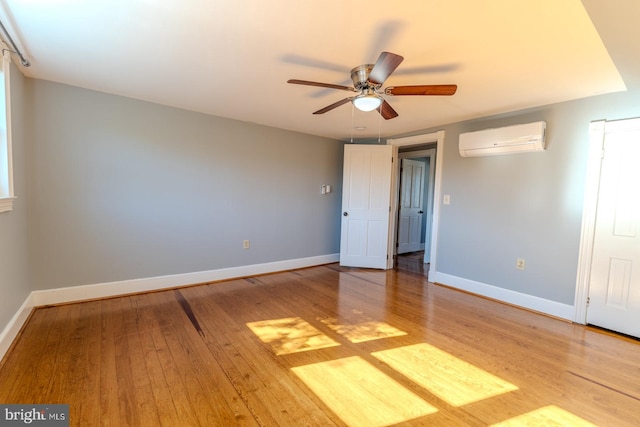 unfurnished bedroom with light hardwood / wood-style flooring, an AC wall unit, and ceiling fan