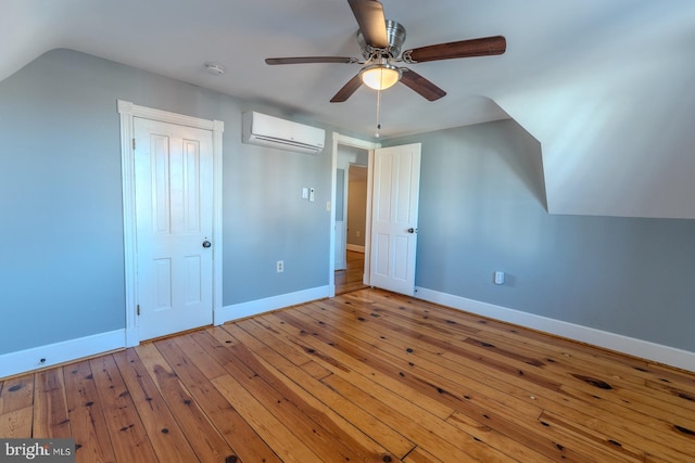 bonus room featuring lofted ceiling, light hardwood / wood-style flooring, a wall mounted air conditioner, and ceiling fan