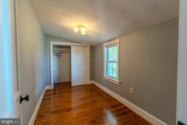 unfurnished bedroom with dark wood-type flooring, a closet, and lofted ceiling