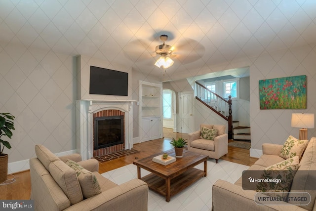 living room featuring ceiling fan, hardwood / wood-style flooring, and a fireplace