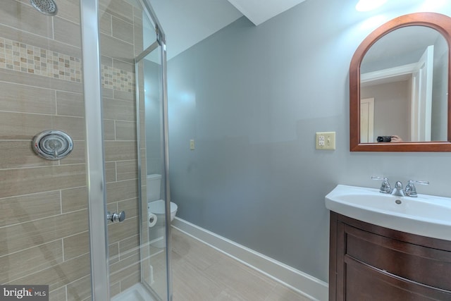 bathroom with vanity, toilet, and a shower with door