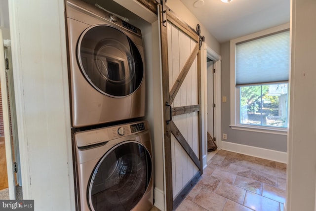 laundry area with stacked washer / dryer and a barn door