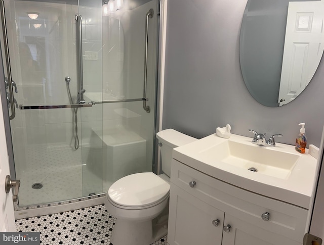 bathroom with vanity, tile patterned floors, toilet, and a shower with door