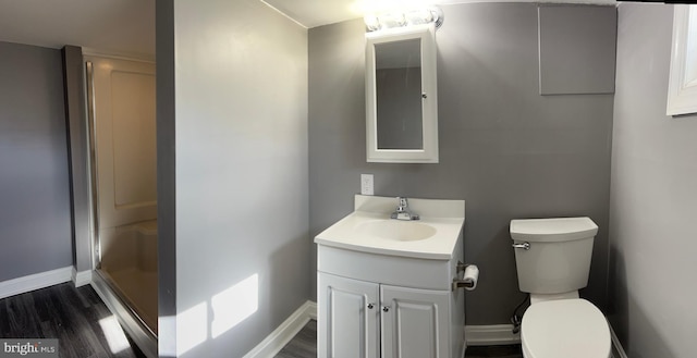 bathroom featuring hardwood / wood-style floors, vanity, toilet, and a shower